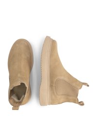 Beige suède Chelsea boots met zij-elastische panelen en trekflappen, één boot vanboven bekeken en de andere van de zijkant.