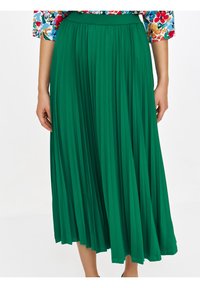 Zielona plisowana spódnica midi z szerokim pasem, teksturowanej tkaniny i zwiewnym kroju, idealna do dynamicznych ruchów i warstwowego stylizowania.