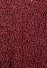 Detaillierte Nahaufnahme von bordeaux-rotem Spitze-Stoff mit floralem und blättrigem Muster, gewebt in einem durchsichtigen, strukturierten Material.