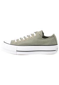 Olive green canvas sneakers with white rubber sole, black stripe, white laces, and gold eyelets. Features a rounded toe and low-top design.