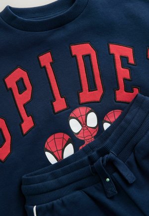 Sudadera navy con la inscripción roja "SPIDER", que presenta tres diseños de Spider-Man. Combinada con pantalones de chándal navy, con cinturilla elástica y cordón.