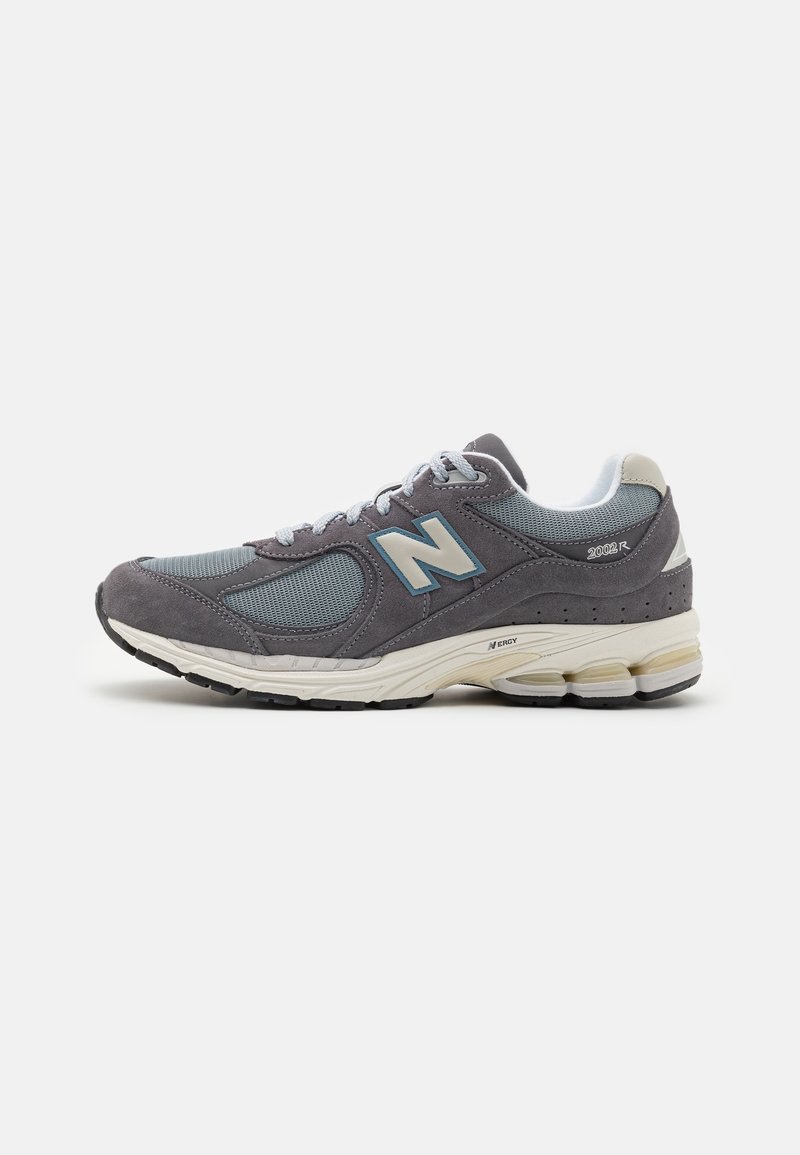Basket New Balance 2002R grise avec tige en mesh et daim, semelle intermédiaire blanche amortie et semelle extérieure en caoutchouc noir, vue latérale sur fond blanc.