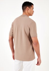 Īsās piedurknes polo krekls gaismas bežā audumā ar teksturētu vafeles rakstu, ar klasisku apkakli un taisnu malu.