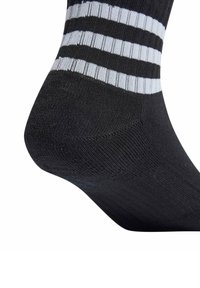 Czarna skarpetka do kostek z poziomymi białymi paskami blisko góry. Lekki, dziany materiał o gładkiej teksturze. Wzmocniona strefa pięty.