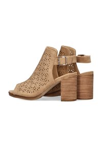 Zapatos de tacón abierto color beige con patrones geométricos recortados, correa trasera y tacón de bloque texturizado. Fabricados con material similar al ante.