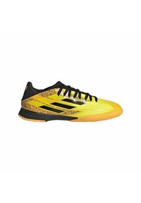 Żółto-czarne buty sportowe z teksturowaną cholewką, zakrzywioną sylwetką, smukłym designem i gumową podeszwą z wyraźnymi wzorami drukowanymi.