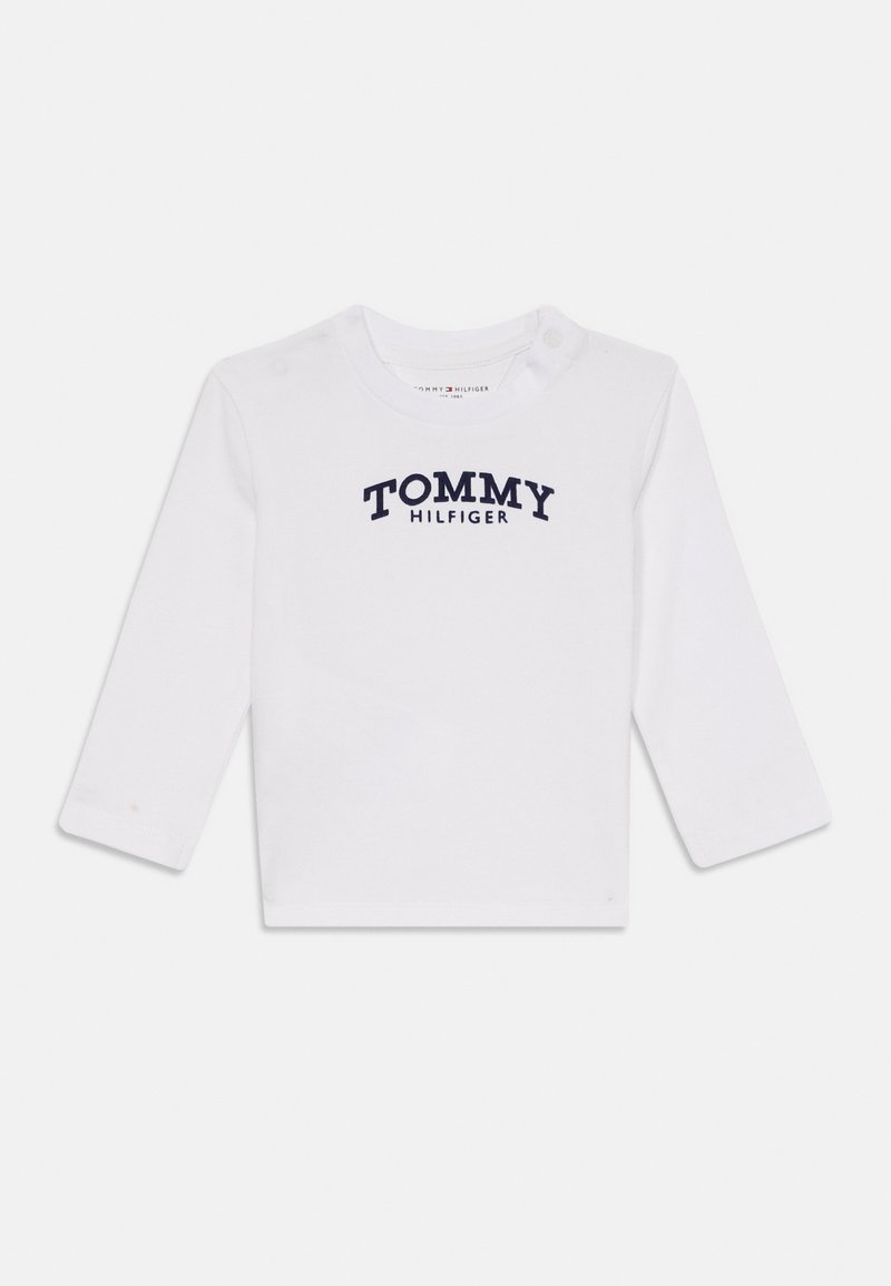 Cămașă albă cu mâneci lungi din bumbac, cu un logo în culori bleumarin "TOMMY HILFIGER" pe piept și nasturi cu capsenă pe umăr.