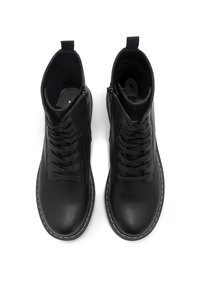 Botas negras hasta el tobillo con un upper de cuero suave, punta redonda, diseño con cordones, cremallera lateral y costuras en blanco contrastantes alrededor de la suela.