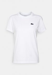 T-shirt en coton blanc avec un col rond, des manches courtes et un petit logo crocodile marine sur la poitrine gauche.