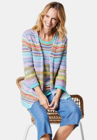 Multikleuren cardigan met een gestreept patroon, met lichtblauwe, roze en oranje tonen. Gecombineerd met een effen turquoise top en denim shorts.