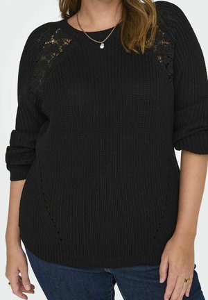 Black knit sweater with a textured pattern and open lace detailing on the shoulders. Features rolled sleeves and a relaxed fit.
