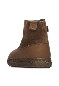 Botas de tobillo marrones hechas de ante y cuero, con una suela texturizada, un tacón ligeramente elevado y un acento cosido a lo largo de la base.