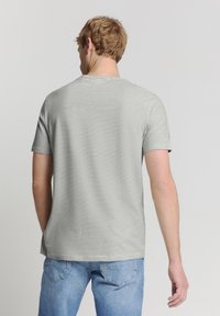 Grijs gestreept t-shirt met korte mouwen, een ronde halslijn en zachte stof, gecombineerd met blauwe denim jeans. Zichtbare naden en een casual pasvorm.