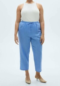 Jasnoniebieskie, luźne spodnie z elastycznym pasem i sznurkiem. Połączone z białą bluzką na ramiączkach i cielistymi czółenkami na szpilce.