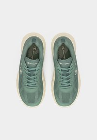 Ζευγάρι πράσινα αθλητικά παπούτσια Champion με μπεζ σόλες, δεμένα και ορατά από πάνω σε λευκό φόντο.