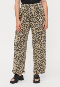 Leopardprint wijde broek gemaakt van ademende stof met een elastische tailleband. Het ontwerp heeft een beige basis met zwarte en bruine vlekken.