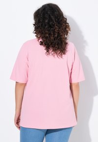 Różowa, oversize'owa koszulka z krótkim rękawem, wykonana z miękkiej bawełny. Z tyłu ma okrągły dekolt i luźny krój.