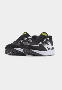 Ζευγάρι από ασπρόμαυρα παπούτσια τρεξίματος New Balance με επάνω μέρος από δίχτυ και υφή από καουτσούκ στη σόλα, σε λευκό φόντο.