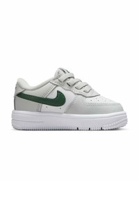 Weißer Low-Top Sneaker mit grünem Nike Swoosh, weißen Schnürsenkeln, perforierter Zehenpartie und strukturiertem weißen Sohlen, Seitenansicht.