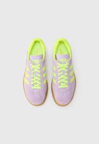 Purpursarkanas zamšādas sporta kurpes ar neona dzelteniem akcentiem, trīs sānu svītrām, gumijas zolī un auklu aizdari.