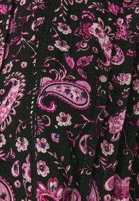 Tessuto nero con un motivo paisley e floreale in rosa e bianco, accentuato da piccole paillettes nere e una cucitura decorativa.