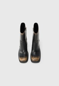 Bottines en cuir noir avec un bout carré et un effet dégradé brun sur la zone des orteils. Présentent une fermeture éclair sur le côté pour un enfilage facile.