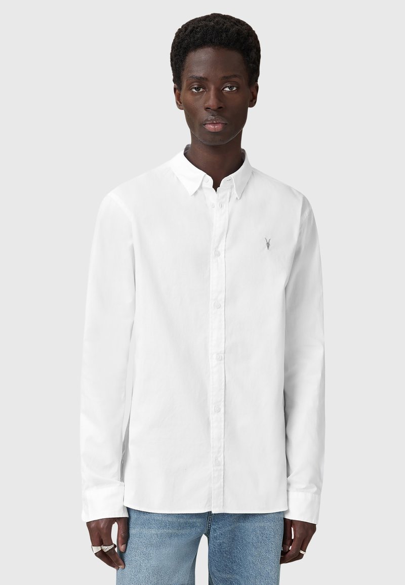 Camicia bianca a maniche lunghe con colletto button-down, dotata di un piccolo logo argento sul petto e una superficie in cotone liscia.