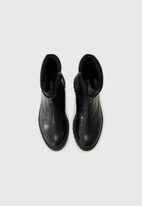 Bottes noires à la cheville avec un dessus en cuir lisse, des fermetures éclair sur les côtés, des bouts ronds et des semelles en caoutchouc texturé pour une bonne adhérence.