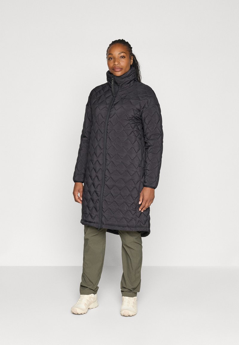 Black quilted long coat with a high collar, featuring a zip closure and side pockets, worn over olive green pants and light footwear.