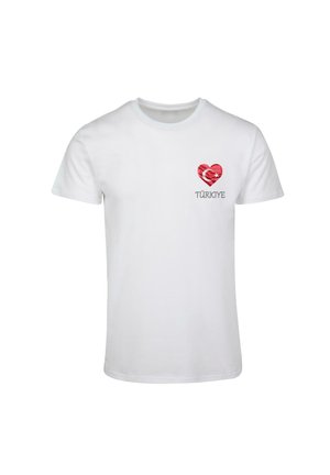 Biała bawełniana koszulka z grafiką serca w czerwono-białym wzorze oraz napisem "TÜRKİYE" wydrukowanym poniżej na czarno. Krótkie rękawy.