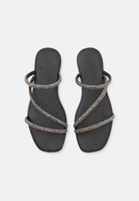 Sandales plates noires avec de fines lanières croisées scintillantes et un design à bout carré sur fond blanc.