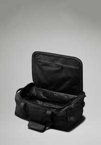 Svart duffelväska gjord av slitstarkt material, med ett zip-lock huvudfack, ett inre meshfack och robusta handtag.