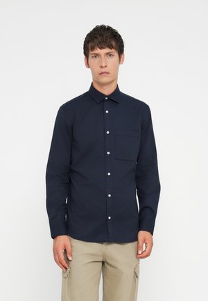 Ναυτικό πουκάμισο μακρυμάνικο κατασκευασμένο από ανάλαφρο ύφασμα, με γιακά που κουμπώνει, μπροστινή τσέπη και λευκά κουμπιά. Σχεδίαση ίσιας που hem.