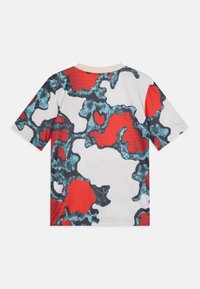 Camisa de manga corta de poliéster con un patrón abstracto colorido en rojo, negro y azul sobre un fondo blanco. Textura suave.