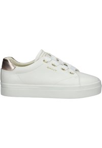 Sneaker bianco con tomaia in pelle liscia, dettagli dorati e capsula metallica sul tallone. Caratterizzato da lacci piatti e suola in gomma testurizzata.