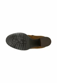 Hnědá nubuková podrážka se strukturovanou černou gumovou podešví s drážkami a mírným podpatkem. Minimalistický design bez viditelného kování.