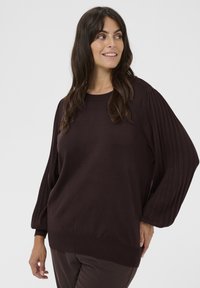 Donkerbruine trui met lange, geribbelde pofmouwen en een ronde halslijn. Zachte textuur en een comfortabele pasvorm, met een geribbelde onderkant.