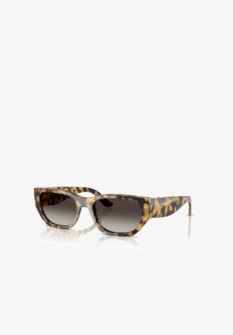 Gafas de sol carey con un amplio diseño de ojo de gato, lentes de gradiente oscuro y la marca "vogue" en dorado en las patillas. Material plástico suave.