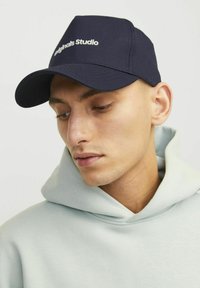 Casquette bleu marine en tissu durable avec le logo "Originals Studio" en blanc, à visière courbée et silhouette structurée.
