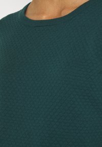 Türkiser Pullover mit einem strukturierten, diamantförmigen Strickmuster. Verfügt über einen runden Halsausschnitt und weichen Stoff, der sein gemütliches Erscheinungsbild unterstreicht.