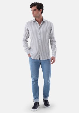 Light gray striped button-up shirt, long sleeves, paired with light blue jeans and dark sneakers. Smooth fabric with a tailored fit.