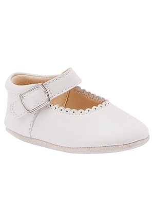 Chaussure Mary Jane en cuir blanc avec bord festonné, bride ajustable avec boucle argentée, intérieur doux couleur beige et semelle lisse.