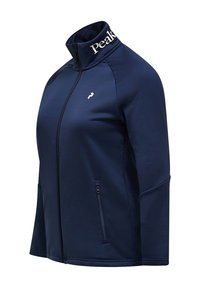 Giacca zip con collo alto di colore blu navy, realizzata in un tessuto liscio ed elastico. Presenta un piccolo logo sul petto e una tasca con cerniera.