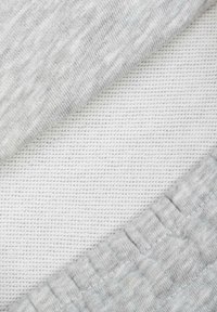 Szary, teksturowany materiał nakładający się na biały, drobno tkany materiał. Szary ma lekko prążkowany wzór oraz miękkie, gładkie wykończenie.