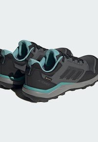 Zapatos de senderismo negros con parte superior texturizada, detalles en color azul verdoso y suela gris. Presenta una etiqueta GORE-TEX y un patrón de tread resistente.