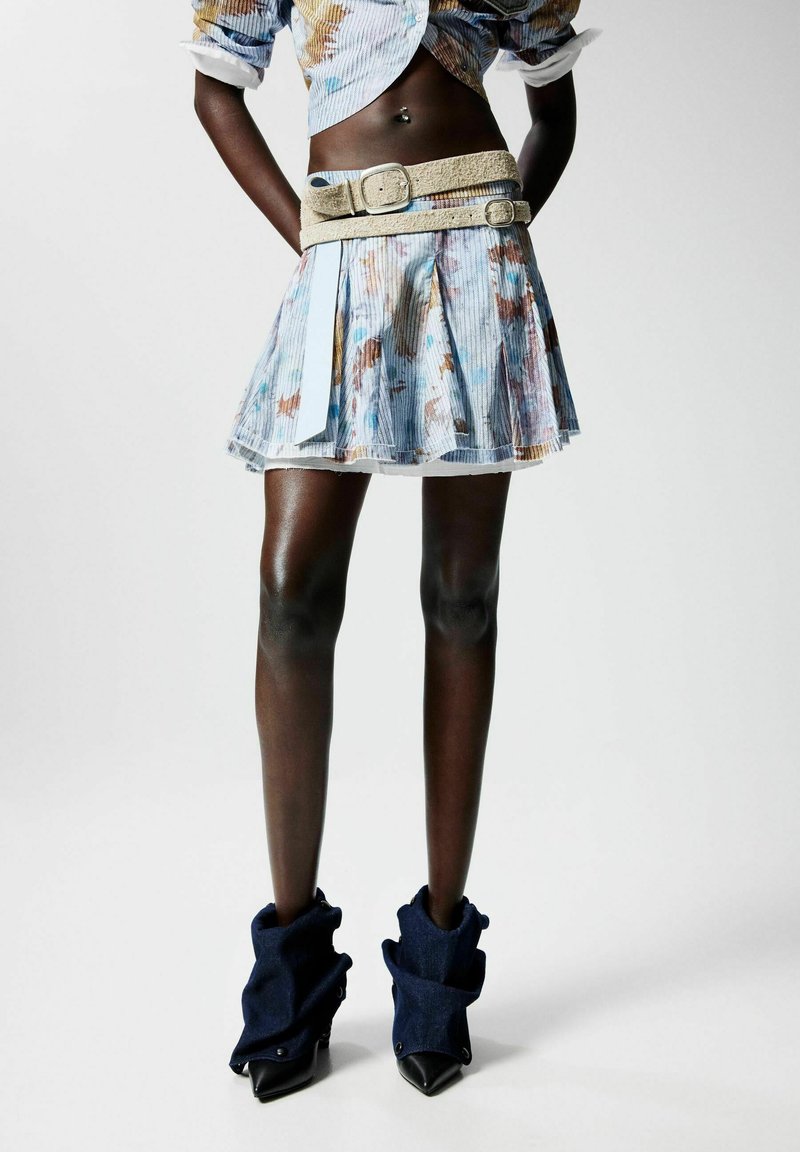 Kék és többszínű csíkos szoknya, redőzött kialakítással, fekete magassarkú csizmával, farmerpánttal. Beigelt öv is tartozik hozzá.