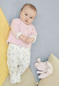 Pysjtøjssæt til spædbørn med en pink top lavet af blødt stof og hvide bukser med et kanin- og blomsterdesign. Inkluderer en blød kaninlegetøj.
