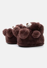 Smeđe plišane papuče u obliku medvjedića s zaobljenim dizajnom, mekanom krznom i crnim potplatom. Imaju male uši i izvezene detalje lica.