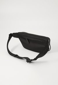 Black fabric crossbody bag with a sleek design, featuring a zippered compartment and adjustable strap with embossed branding.