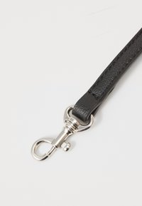 Correa de piel negra con un acabado texturizado; cuenta con un cierre metálico en tono plata, combinando funcionalidad con un material duradero.